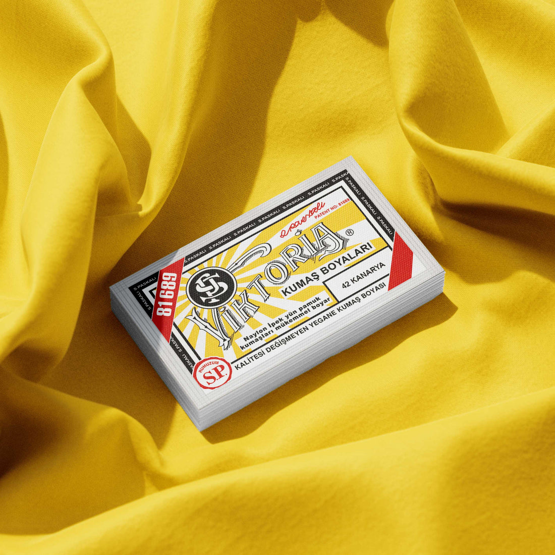 Pack of canary yellow fabric dye placed on a vibrant yellow fabric background